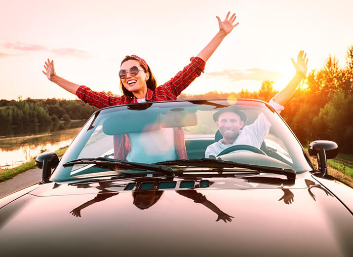 Zwei Freunde sitzen im Cabrio. Sie haben die Arme ausgestreckt und hören Musik. Zwei Freunde sitzen im Cabrio. Sie haben die Arme ausgestreckt und hören Musik.