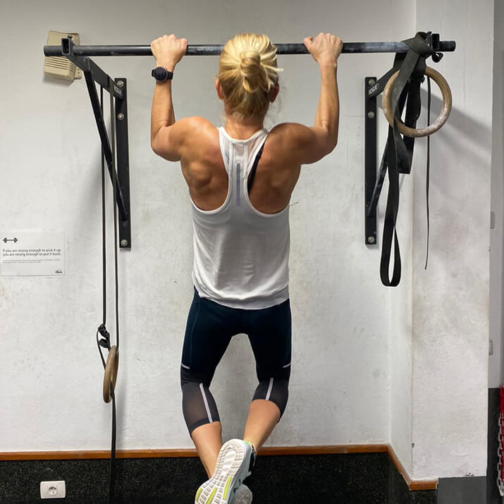 Eine Sportlerin zieht sich mit einem Klimmzug nach oben. Eine Sportlerin zieht sich mit einem Klimmzug nach oben.
