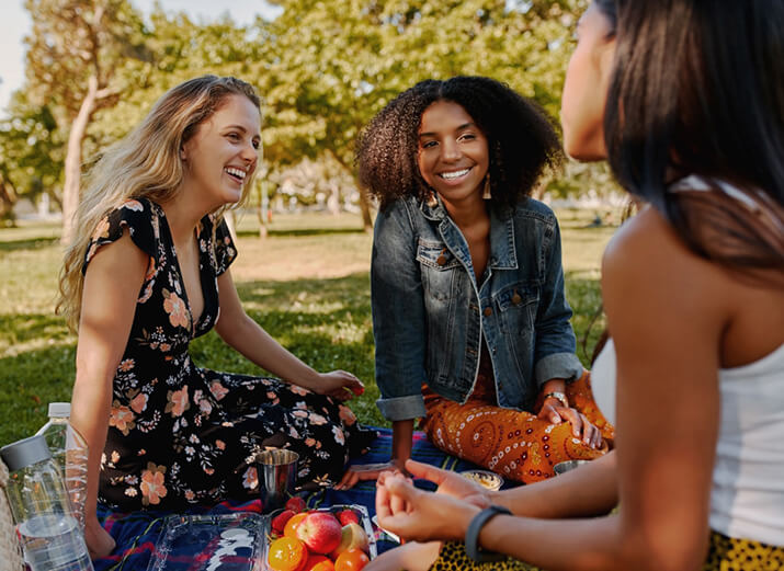 Drei Freundinnen picknicken und unterhalten sich. Drei Freundinnen picknicken und unterhalten sich.
