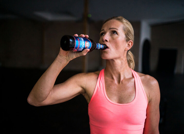 Eine Sportlerin trinkt ein alkoholfreies Bier aus einer Flasche. Eine Sportlerin trinkt ein alkoholfreies Bier aus einer Flasche.