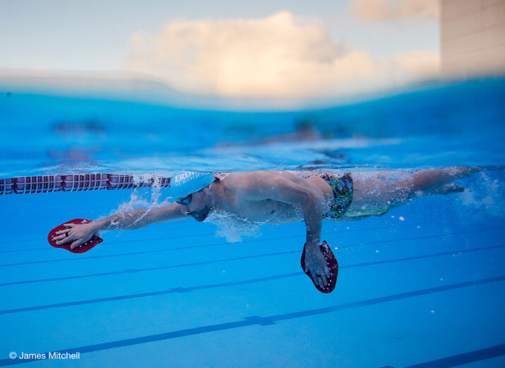 Ein Schwimmer krault mit Paddles. Ein Schwimmer krault mit Paddles.