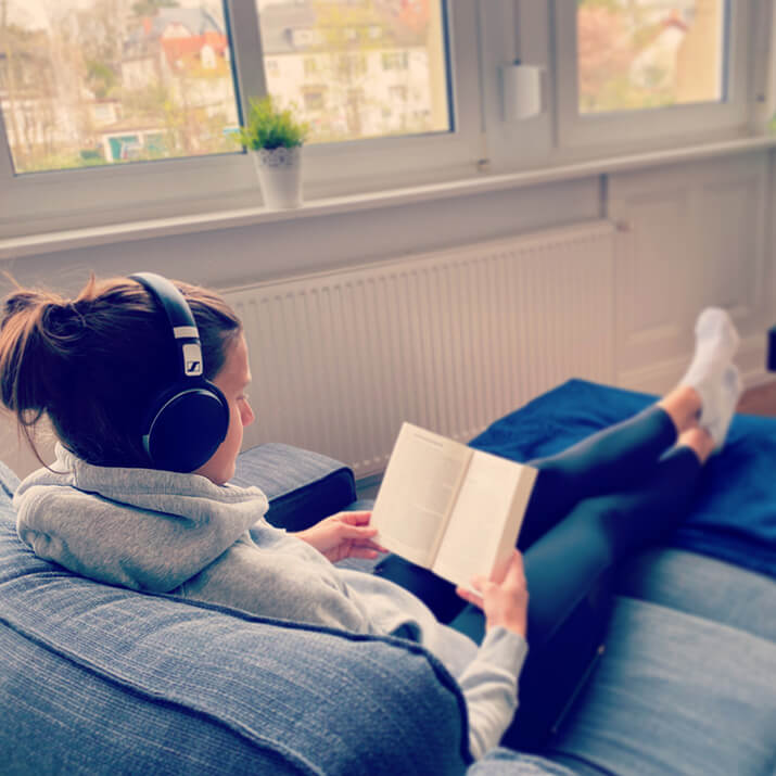 Eine Frau sitzt auf dem Sofa und regeneriert beim Lesen eines Buches. Eine Frau sitzt auf dem Sofa und regeneriert beim Lesen eines Buches.